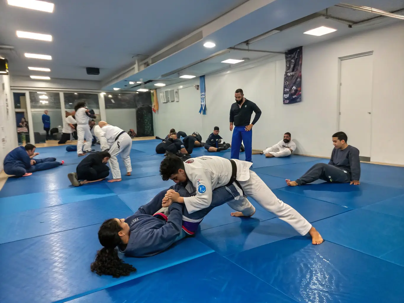 A diverse group of students practicing jujitsu techniques, showcasing joint locks and grappling maneuvers in a controlled setting.